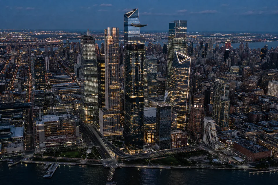 Night skyline of a dense financial district with illuminated office towers along a harbor