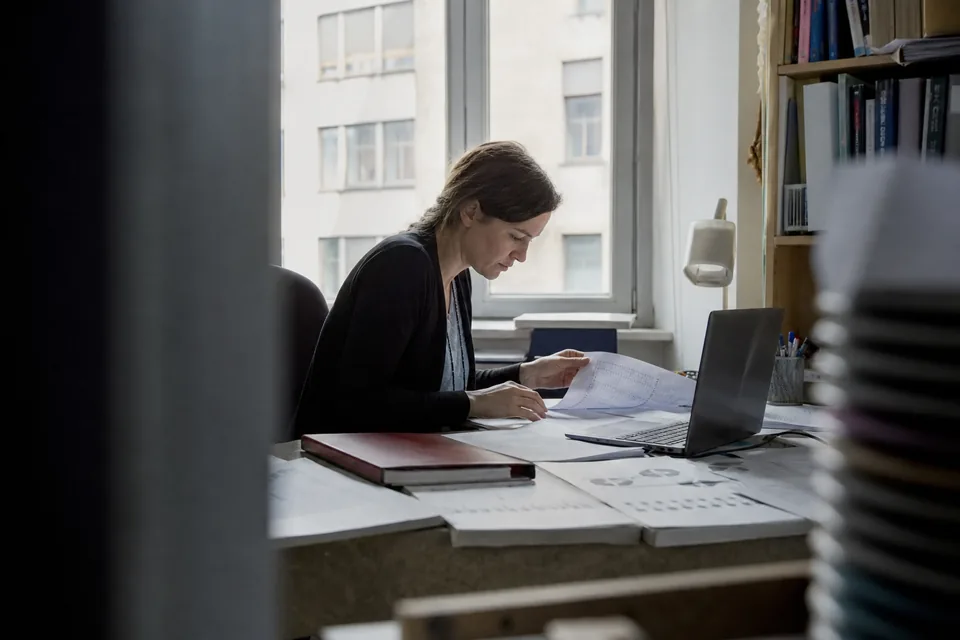 Research desk with printed data tables and a laptop in a quiet office